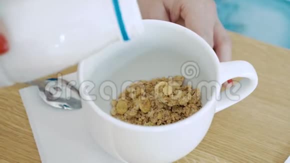 健康的早餐女性手把牛奶或酸奶倒入一碗谷类食品中视频的预览图