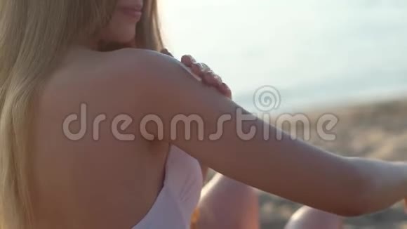 年轻苗条的漂亮女孩在她的身上涂上防晒霜视频的预览图