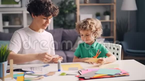 有创意的家庭妈妈和小孩子用纸剪刀和胶水做拼贴画视频的预览图