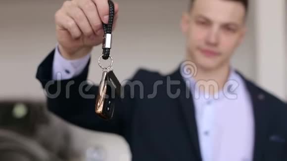 特写镜头在一个现代化的展厅里一个穿着西装的男人手里拿着一辆新车的钥匙视频的预览图