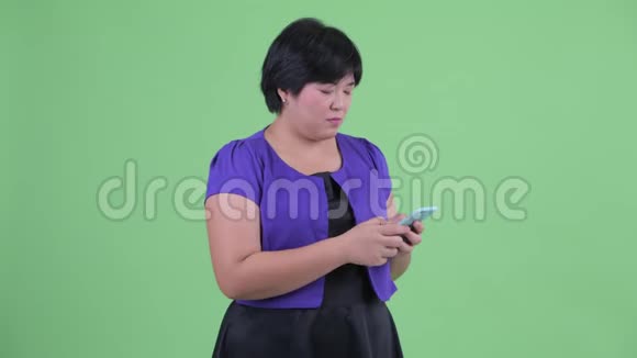 快乐的年轻超重的亚洲女人用电话看起来很惊讶视频的预览图