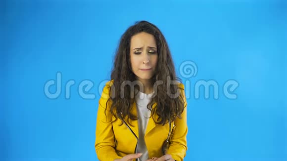 失望和一个非常悲伤的年轻女人几乎哭在工作室蓝色背景视频的预览图
