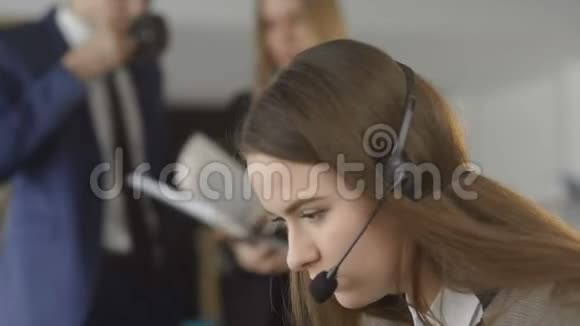 穿西装的女商人戴着耳机说话看着笔记本电脑做笔记男客户支持经理翘首以待视频的预览图
