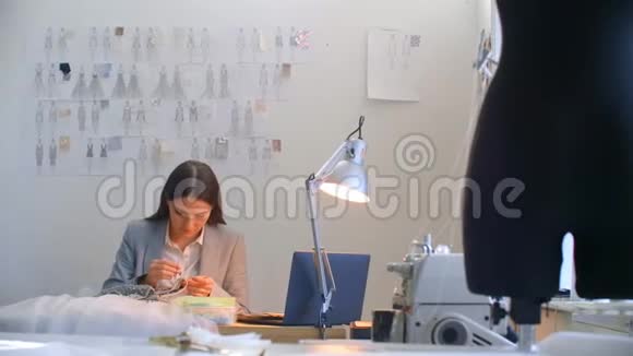 一位年轻的女设计师在工作室里做一件连衣裙裁缝工作室缝制珠子和珠宝裁缝视频的预览图