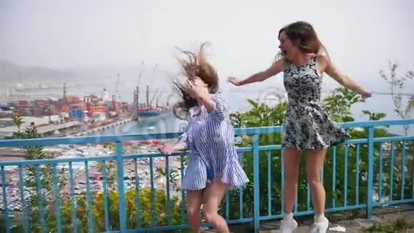 两个年轻女子正在观景台上跳舞关于城市的背景视频的预览图