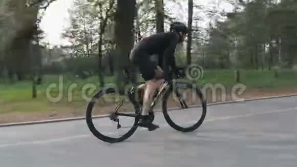 强壮瘦瘦的骑自行车的人在公园里骑自行车高速骑车上坡出鞍从侧面看自行车比赛视频的预览图