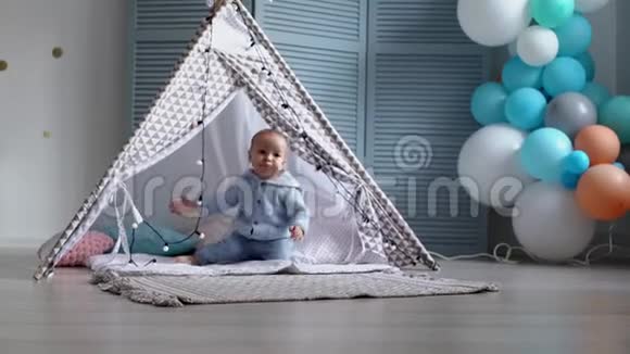 一个快乐可爱的婴儿在孩子们的帐篷里打着花环视频的预览图