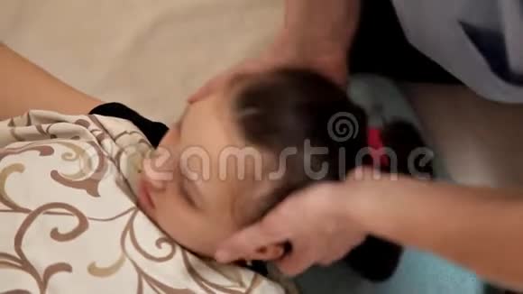 一个小女孩在一次骨病治疗会上的特写治疗师操纵孩子头部按摩视频的预览图