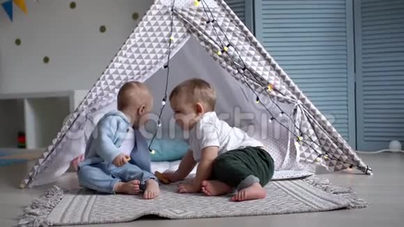 两个可爱的婴儿在孩子们的帐篷停下来吃饼干视频的预览图