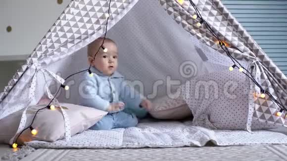 一个快乐可爱的婴儿在儿童帐篷里玩花环视频的预览图
