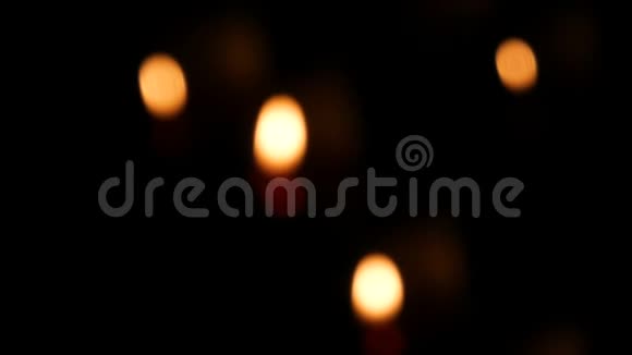 在一个天主教的寺庙里红色的圆形燃烧的葬礼蜡烛在沙子上暗离焦时的烛光视频的预览图