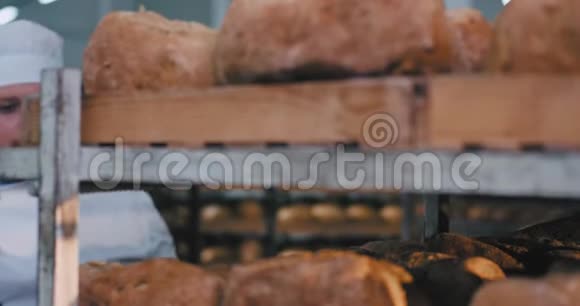 面包店厨房里的一个大面包师傅正享受着货架上新鲜烘焙面包的味道他做了一张可爱的脸视频的预览图