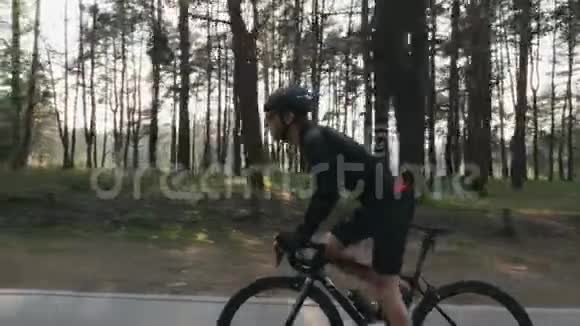 强壮的骑自行车的人在公园里骑自行车阳光透过树木照耀侧跟射击自行车的概念慢动作视频的预览图