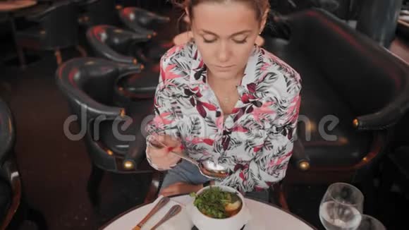 漂亮的女法国女人穿着一件杂色衬衫吃一道传统的法国洋葱汤里面有面包和青菜视频的预览图