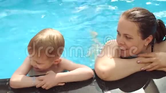 一位年轻的母亲和她的儿子在游泳池里休息慢动作视频的预览图