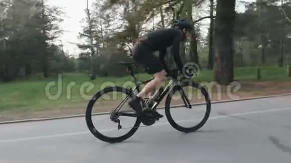 强壮瘦瘦的骑自行车的人在公园里骑自行车高速骑车上坡出鞍从侧面看自行车比赛视频的预览图