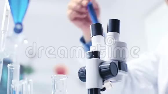 化学家用低角度镜头分析试管然后在显微镜下观察视频的预览图