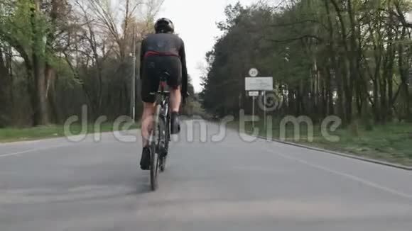 骑自行车的自行车骑自行车近距离观看腿部肌肉公园里骑自行车的人穿着黑色运动服慢动作视频的预览图