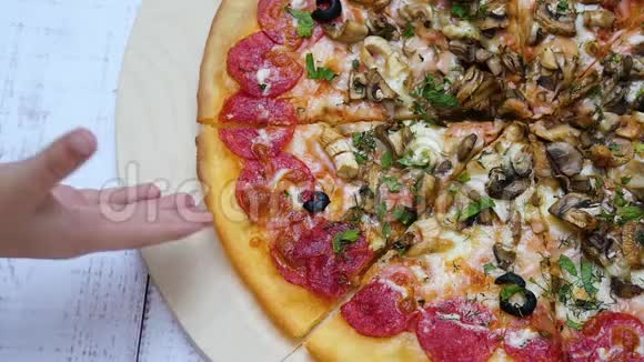 带有意大利香肠特写的披萨放在木桌上孩子手拿一块比萨饼视频的预览图