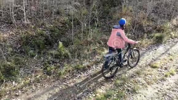 骑自行车的女人骑自行车在乡村道路上的自动森林有乐趣和享受生活空中射击视频的预览图