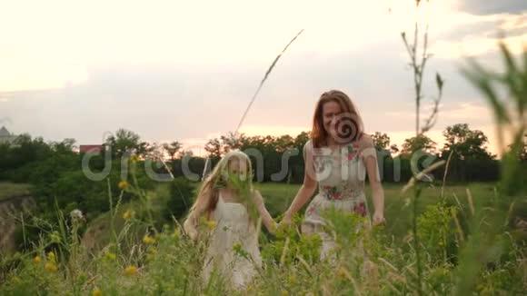 母女俩牵着手在傍晚的草地上奔跑视频的预览图