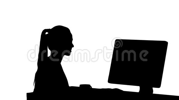 剪影女孩坐在电脑显示器前看着一些微笑视频的预览图