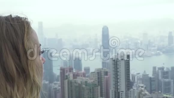 年轻女子从维多利亚峰观看香港城市全景白种人肖像旅游妇女观看全景视频的预览图