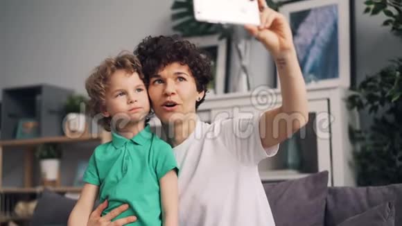 漂亮女孩和可爱的儿子自拍笑着玩着拿智能手机视频的预览图