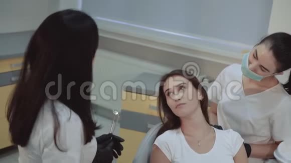 微笑的女孩坐在牙科柜里接受治疗和咨询视频的预览图