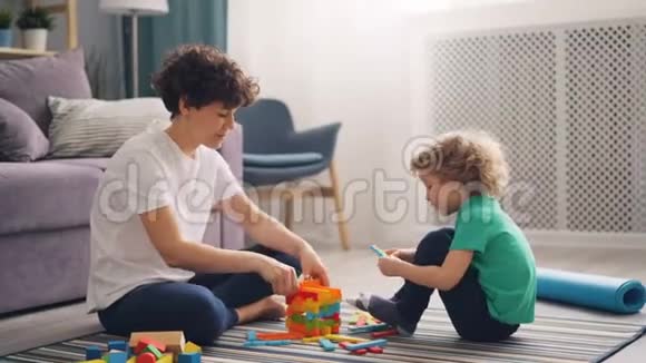 快乐的小男孩在玩木玩具而妈妈在帮他回家视频的预览图