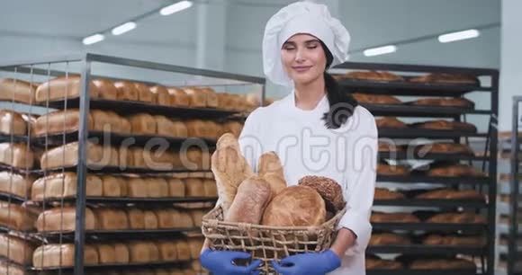 食品厂微笑着一位美丽的大女士在烘焙区她拿着一个新鲜的烘焙面包直视着视频的预览图