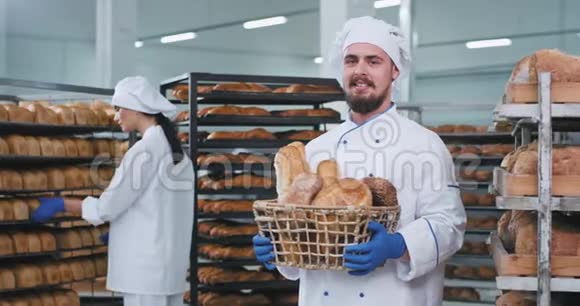 微笑的魅力男人面包师带着一个装满新鲜烘焙面包的大篮子直视着相机微笑着视频的预览图