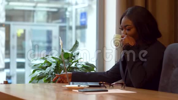 非裔美国女商人手提电脑和纸女孩喝咖啡视频的预览图