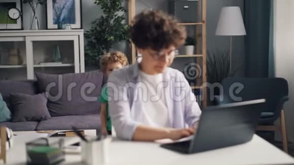 女性自由职业者使用笔记本电脑然后在家玩小孩视频的预览图