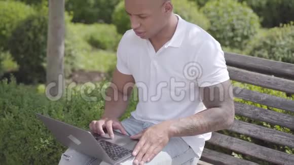 肖像英俊秃顶的中东男子在街上工作笔记本电脑坐在长凳上自由职业概念这就是视频的预览图