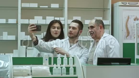快乐的药剂师和实习生团队通过智能手机在工作场所自拍视频的预览图
