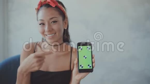 一位女士直视摄像头将手机显示为绿色屏幕视频的预览图