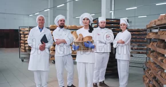 食品行业漂亮的面包师女士和她的同事主要团队直视镜头在一家大面包店微笑视频的预览图