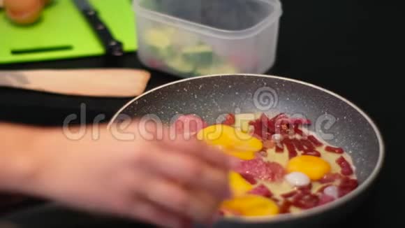 人类早餐在锅上打碎鸡蛋用香肠做煎蛋视频的预览图