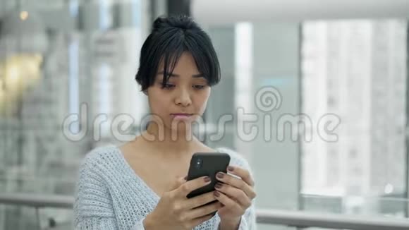 严肃的亚洲女性站在手机上打字时的镜头慢镜头视频的预览图