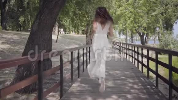 肖像迷人的年轻女孩一头黑发戴着太阳镜穿着白色的夏装穿着一件白色的长裙视频的预览图