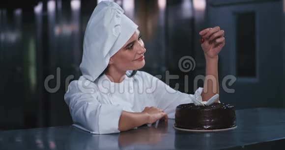 一位年轻迷人的女士高兴地把樱桃小心地放回蛋糕上慢慢地与相机接触视频的预览图