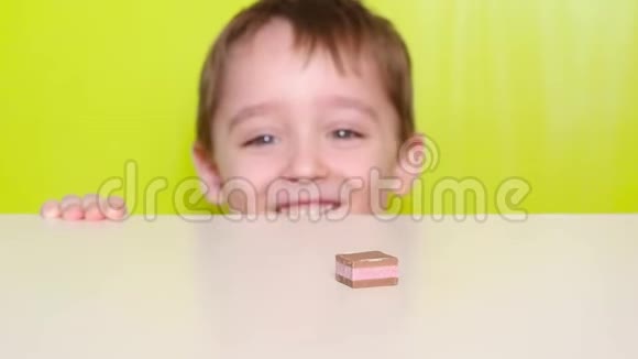 小笑童躲在桌子下面拿出糖果巧克力糖果放在桌子上视频的预览图