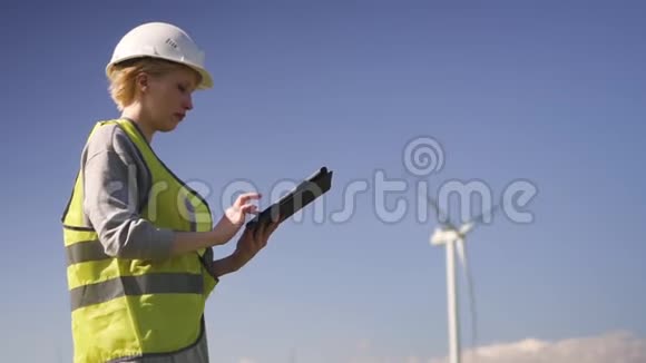 技师站在风力机附近为平板电脑做笔记视频的预览图