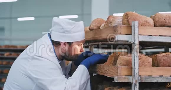 在一家面包店主厨面包师在从工业烤箱起飞后检查面包的质量他看着视频的预览图