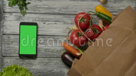 两个新鲜西红柿在蔬菜和智能手机附近滚动视频的预览图
