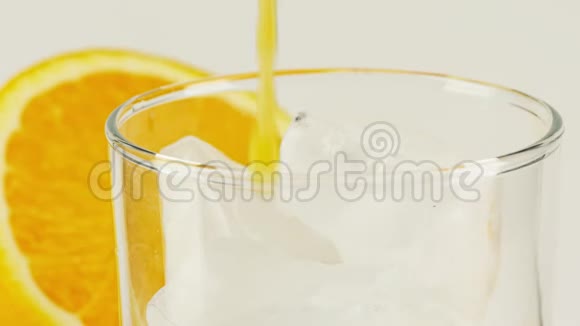 将橙色软饮料倒入装有冰块的玻璃杯中在红色上拍摄特写慢镜头视频的预览图
