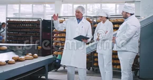 在一家面包店里一位工程师和两个面包师聊了聊他解释了关于自动输送机的说明视频的预览图