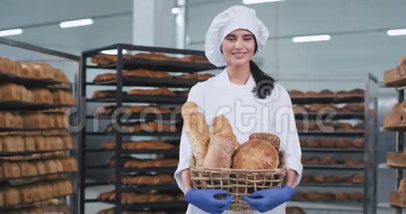 漂亮的年轻面包师女士拿着一个带有有机面包的新鲜老式篮子直视着相机和视频的预览图