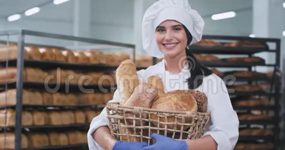 一个漂亮的面包师微笑着她拿着一个篮子里面有新鲜的烘焙面包视频的预览图